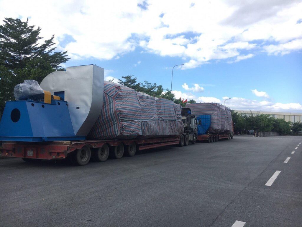 Vận chuyển thiết bị công nghiệp kích thước lớn bằng xe đầu kéo mooc sàn, hàng hóa được che phủ cẩn thận và cố định chắc chắn trong suốt hành trình. van-chuyen-thiet-bi-cong-nghiep-sieu-truong-bang-mooc-san-chuyen-dung