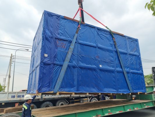 Cẩu nâng kiện hàng công nghiệp kích thước lớn đã bọc bạt lên mooc lùn phục vụ vận chuyển hàng siêu trường siêu trọng an toàn đúng quy trình cau-ha-kien-hang-lon-len-mooc-lun-an-toan-dung-ky-thuat-van-chuyen