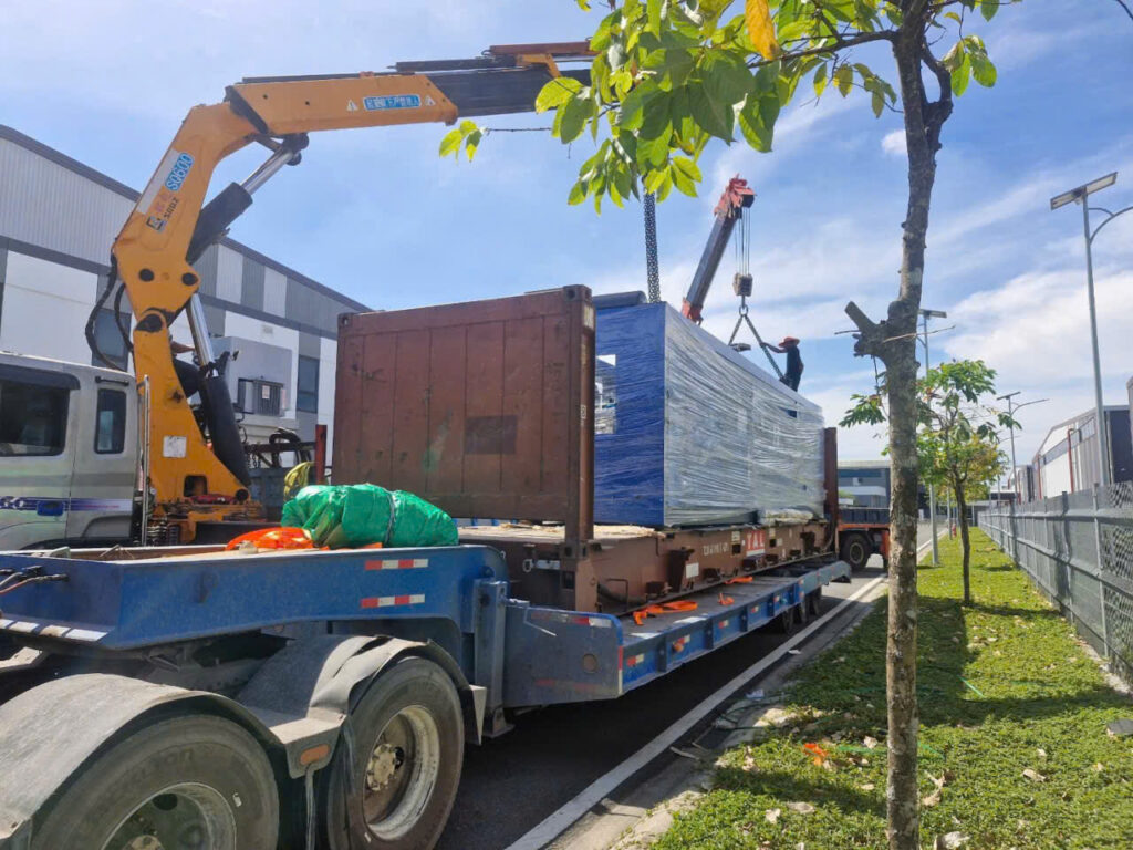 Xe cẩu hỗ trợ cố định thiết bị công nghiệp trên mooc sàn trước khi vận chuyển từ Tây Ninh đi Đà Nẵng, bảo đảm an toàn và đúng quy trình kỹ thuật. cau-co-dinh-hang-tren-mooc-san-truoc-khi-van-chuyen-di-da-nang-an-toan-chuyen-nghiep