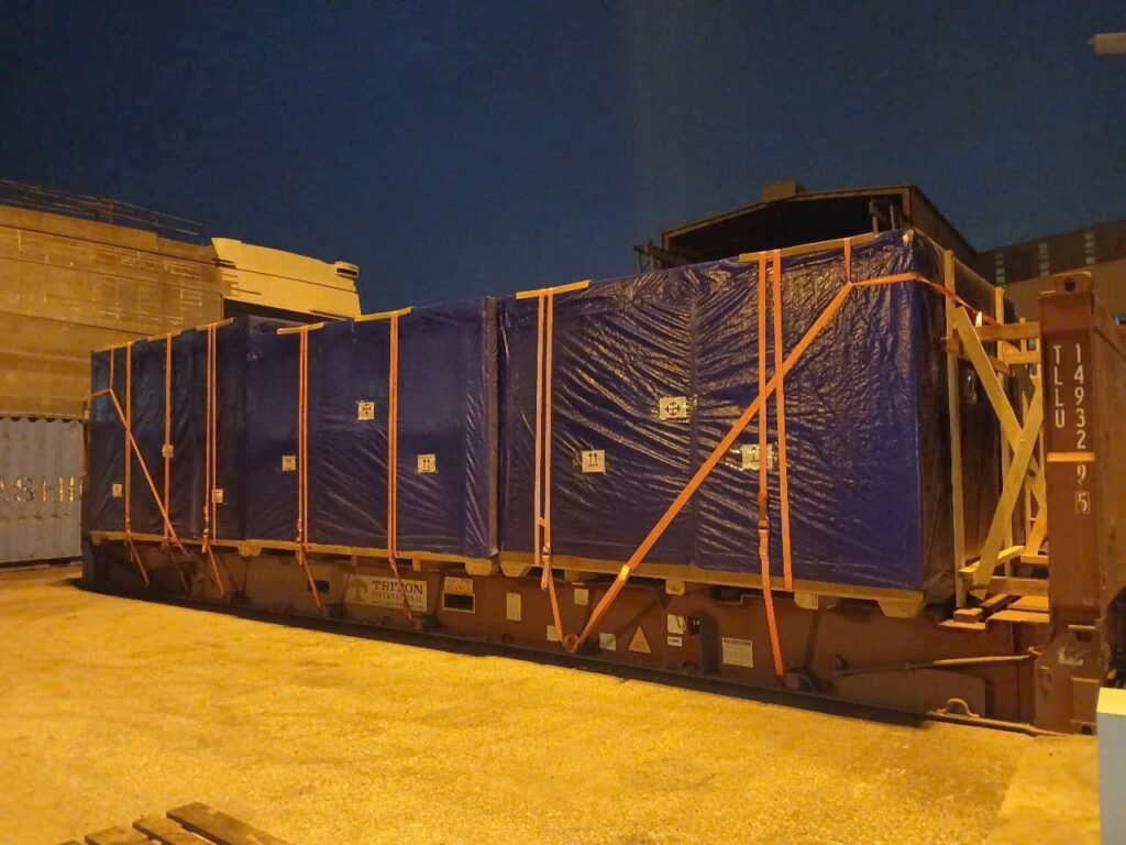 Hàng hóa được chằng buộc bằng dây tăng đơ, phủ bạt chống bụi và cố định chắc chắn trên mooc sàn trước khi vận chuyển đến Khánh Hòa an toàn. chang-buoc-co-dinh-hang-hoa-tren-mooc-san-truoc-khi-van-chuyen-an-toan-dung-chuan