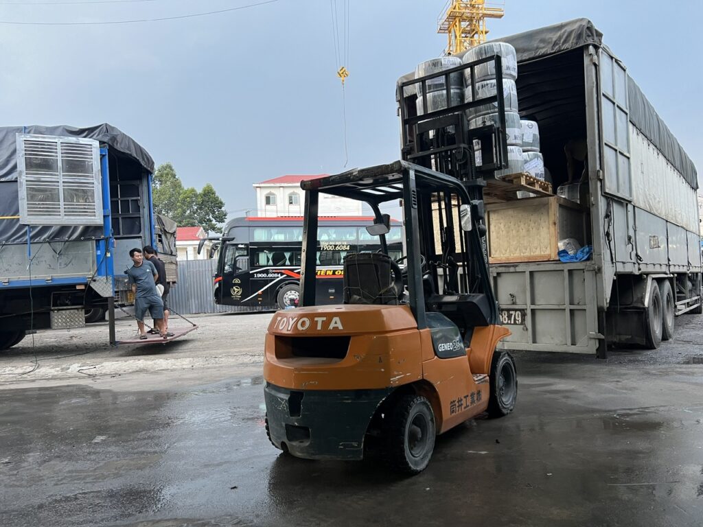 Dùng xe nâng hạ hàng hóa xuống xe tải tại điểm giao nhận, hỗ trợ đưa từng kiện hàng xuống đúng vị trí và thuận tiện cho quá trình bàn giao. dung-xe-nang-ha-hang-hoa-xuong-xe-tai-tai-diem-giao-nhan