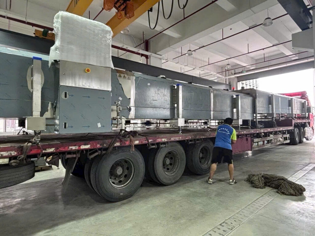 Máy móc thiết bị công nghiệp cỡ lớn được xếp trên xe đầu kéo mooc sàn, sử dụng dây chằng buộc cố định hàng hóa chắc chắn trước khi vận chuyển đường dài. may-moc-thiet-bi-cong-nghiep-co-lon-duoc-xep-tren-xe-dau-keo-mooc-san